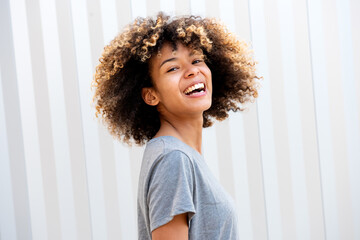 Side of cheerful african american teen girl against white wall