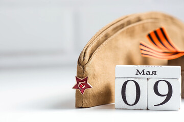 The holiday is May 9. St. George ribbon, military cap, wooden calendar on a white background. The...