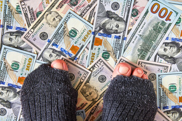 feet in torn holey socks on dollar money