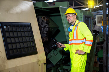 Engineers and skilled technicians are maintaining machinery. Professional technicians are holding a tablet to control machine in industrial plants.