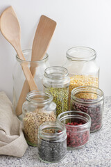 Variety of dry legumes: kidney bean, peas, green gram in glass jars uncooked on white kitchen background, zero waste, eco friendly, balanced diet food, healthy clean eating, vegan protein concept