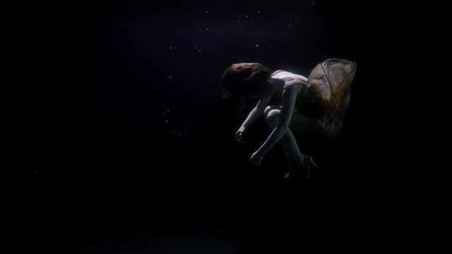 mysterious underwater shot of sinking female body in dark deepness, inside depth of sea or ocean