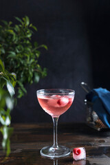 Elegant glass of pink rose champagne with frozen raspberries in ice cube