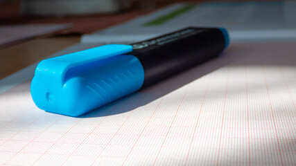 hellblauer Textmarker fokussier auf einem Block mit Millimeterpapier