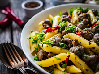 Penne with mushrooms in cream sauce on wooden table

