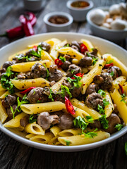 Penne with mushrooms in cream sauce on wooden table
