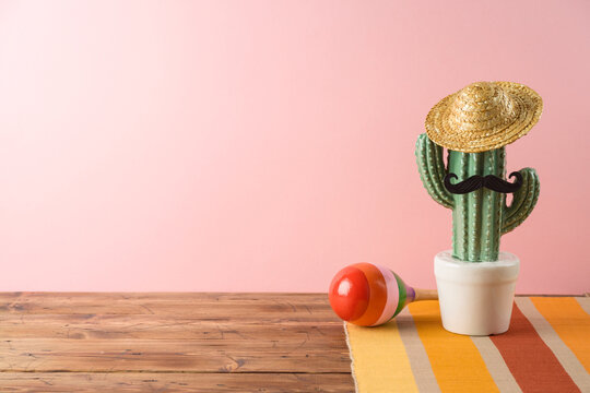 Cinco de Mayo holiday background with Mexican cactus,  party sombrero hat and maracas on wooden table