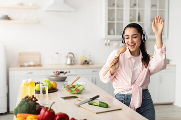 Portrait of smiling young woman singing and dancing in kitchen