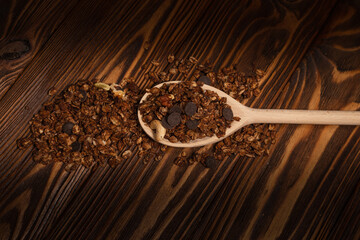 Chocolate granola cereal with nuts in a wooden spoon.