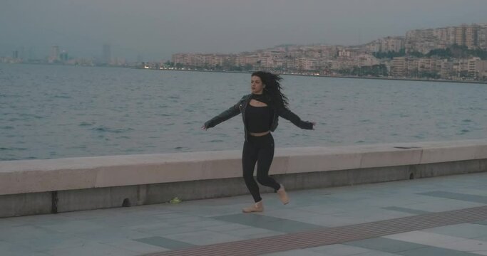 Young beautiful ballet woman is dancing on seaside, beach. Ballerina with ocean, sunset time. Healthy lifestyle, freedom and dance performance concept.