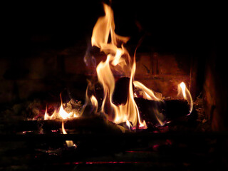 Fire burning in fireplace, close up of orange flames eating firewood