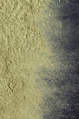 scattered dry matcha tea powder on a black background