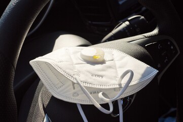 protective medical mask lies on the steering wheel of a car