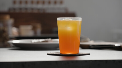 aperitivo with orange soda with ice in tumbler glass to make spritz drink on concrete countertop