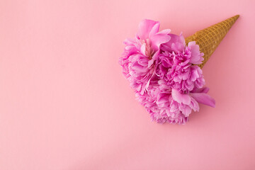 Ice cream cone with pink peonies on the pink background.Top view.Copy space.Spring flowers concept.