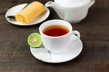Bergamot tea or Earl Grey tea in white cup and fresh bergamot fruit with sliced on brown wooden table.