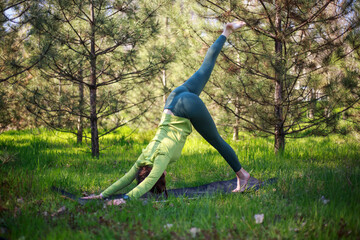 Girl doing yoga in fir park, fitness exercise outdoors, healthy lifestyle and freshness of pure nature