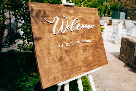 Brown wooden easel with an inscription. Inscription: Welcome to our beginning