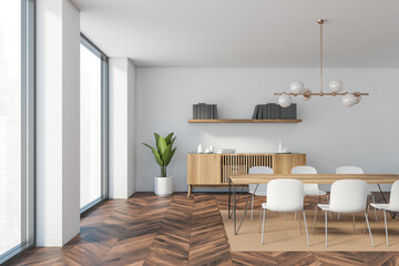 Interior design of luxury living room with stylish commode table and furniture. White wall with book shelf. Modern home decor. Panoramic window.