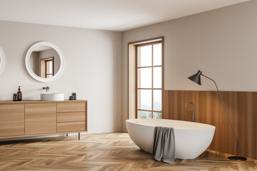 Light bathroom interior with sink and bathtub with lamp on wooden floor