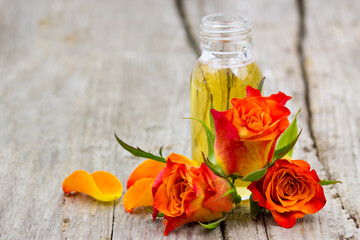bath oil and orange roses on old wooden background