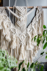 Macrame. Handmade macrame weaving and cotton threads on a rustic wooden stick. Scandinavian style in the interior, boho style. Cozy home