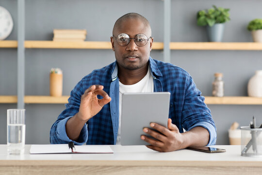 Mature african american man holding digital tablet and looking at camera, recording review video to internet vlog