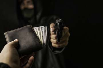 Armed robbery. Man's hand holds out purse of money to robber with gun. Firearm is pointed at...