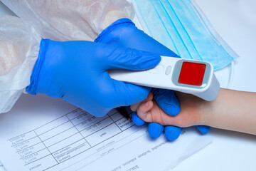 Close-up shot of doctor's hands in medical gloves ready to use infrared thermometer to check body temperature for virus symptoms - Covid-19 epidemic virus outbreak concept.