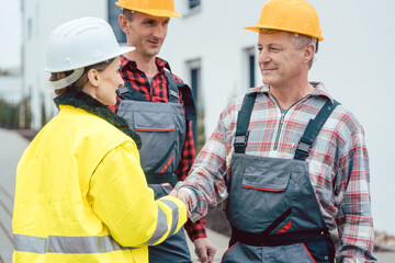 Builder and contractor on construction site shaking hands in acceptance