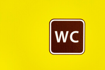 The sign a toilet on a yellow background. Copyspace. abbreviation WC. Symbol of the place bathroom