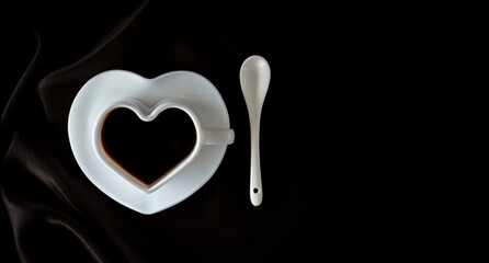 Coffee. Coffee cup on dark fabric or black background. Heart-shaped coffee cup