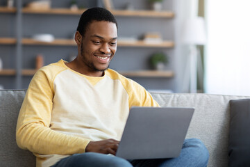 Smiling african american man attending webinar, using laptop
