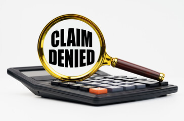 On a white background lies a calculator and a magnifying glass with the inscription - Claim denied