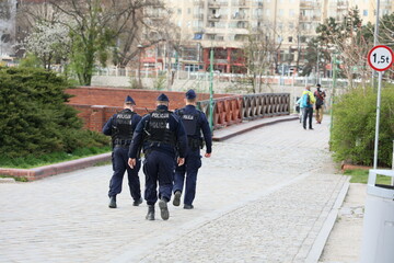 Trzech polskich policjantów na patrolu w miecie. 