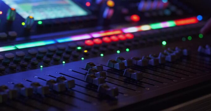The sound engineer adjusts the sound at the concert using a large luminous sound console.
