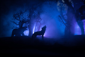Silhouette of howling wolf against dead forest skyline and full moon. Creative artwork decoration.