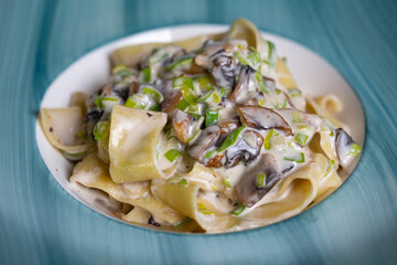 pasta in sauce with mushrooms on a blue plate close-up