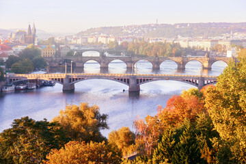 Obraz premium Prague in mist, six bridges on Vltava river in Prague, Czech Republic, on a misty morning in Autumn. Yellow, orange leaves on trees, romantic view.