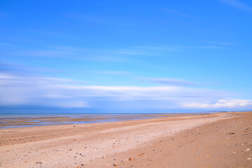 Fototapeta na wymiar La plage de Sword beach à Ouistreham sous un ciel avec des nuages qui bougent en France, en Normandie, dans le Calvados, au bord de la Manche.