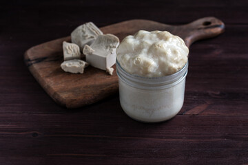 Live yeast on a wooden board and a jar with activated yeast
