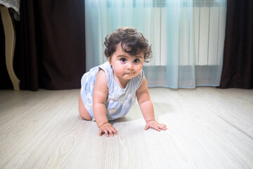 Baby Girl In Summer Dress Sit on wooden floor inside room.