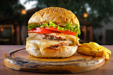 Delicious hamburger with french fries on wooden table with background in restaurant - close up front view.