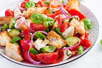 Traditional italian tomato salad panzanella with mozzarella, capers, red onion and croutons. Summer salad.