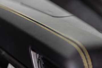 Fine details on this car interior dashboard with yellow stitching on a double row on the seam.