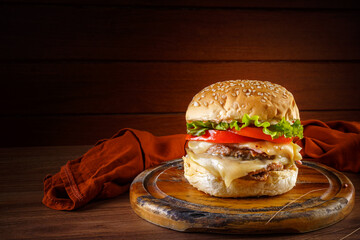 Delicious hamburger on wooden table with rustic wooden background - front view.
