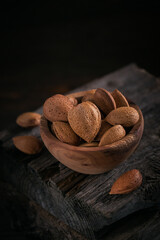 Pile of Almond nuts in a bowl on a dark wooden background