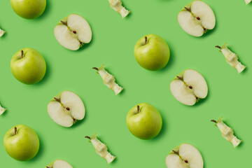 Pattern made with fresh green eaten apples and halves on the green background. Minimal organic fruit concept. Flat lay, top view.
