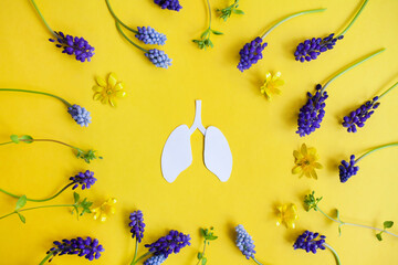 minimalistic white image of lungs on a yellow background in the center of a frame of flowers and...