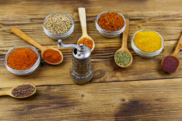 Set of different aromatic spices and spice mill on wooden table